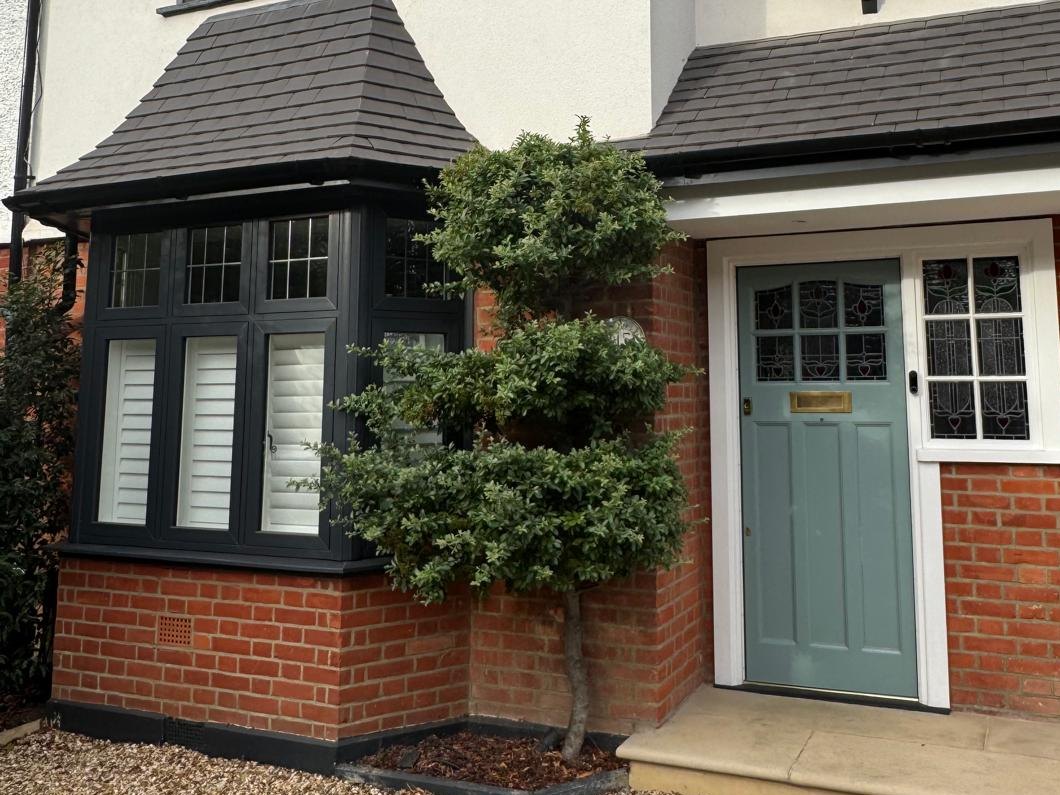 Front of a house with a bay window and a sage green front door