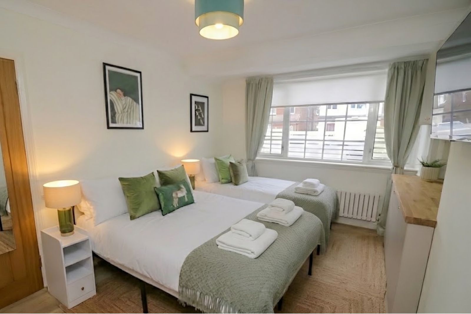 Green bedroom with two beds made up with fresh linen