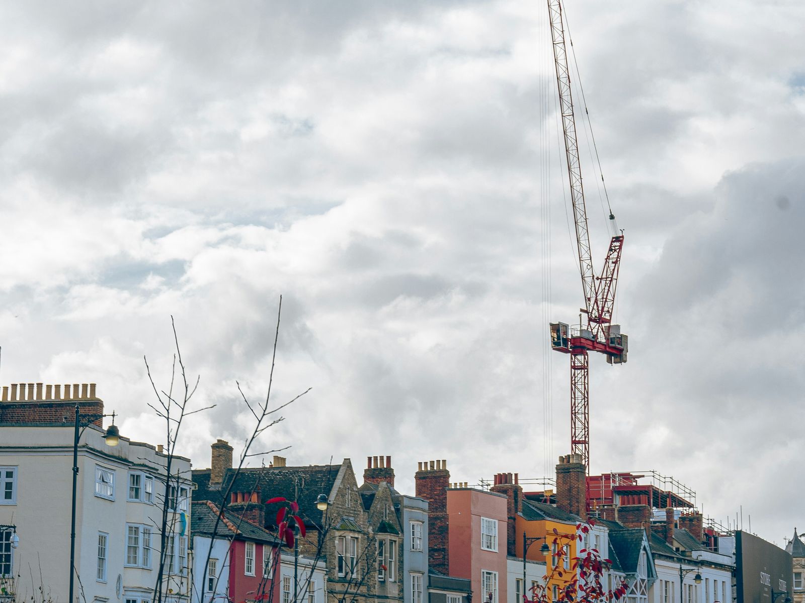 Tower crane on a construction site above a street of town houses